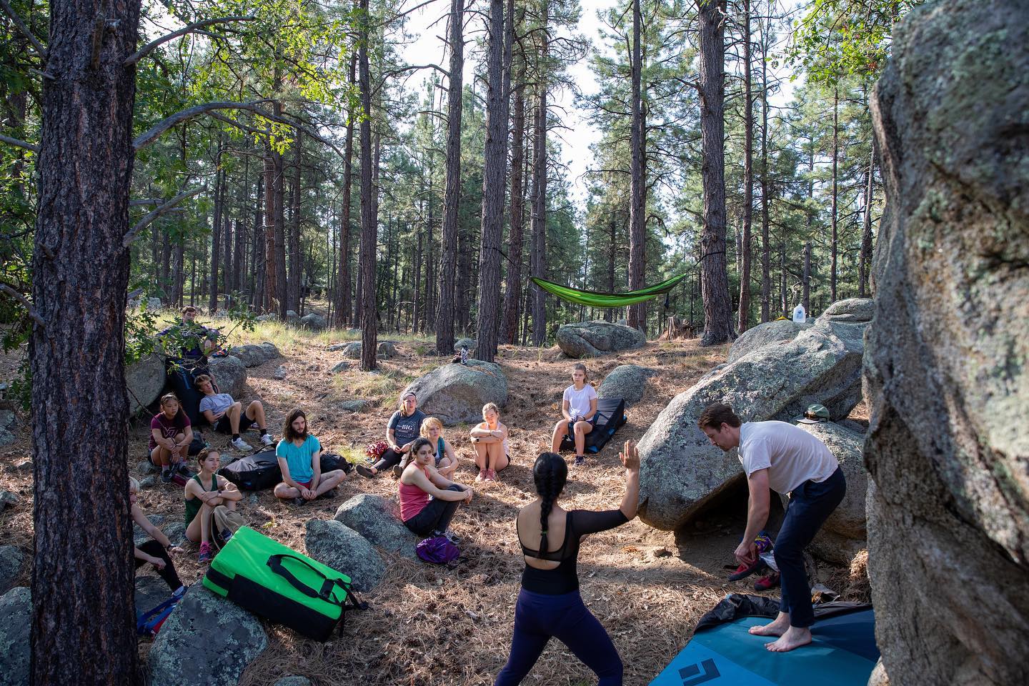 students bouldering and rock climbing in the forest by an ENO hammock