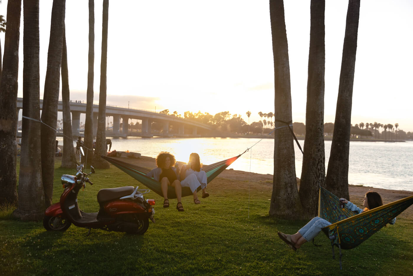 3 people hammocking in 2 ENO hammocks while the sun is setting behind them