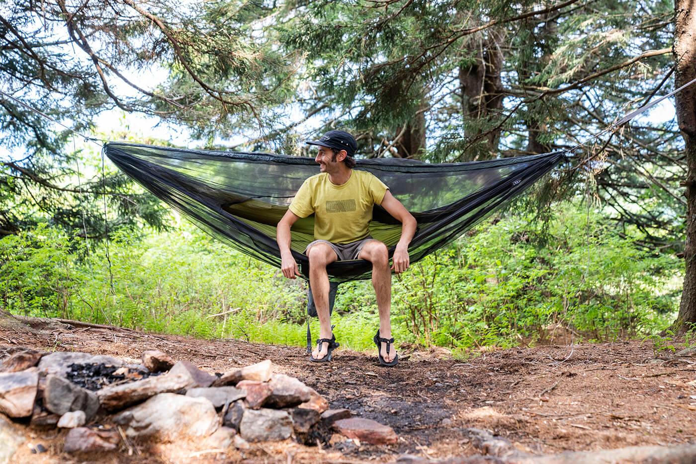 A man sitting in an ENO hammock in the woods