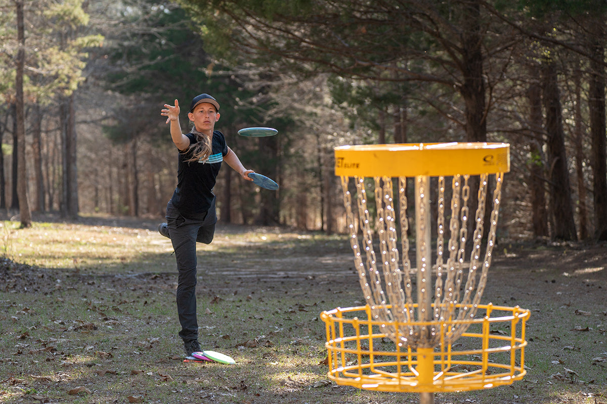 Paige Pierce throws a disc into the goal while disc golfing.