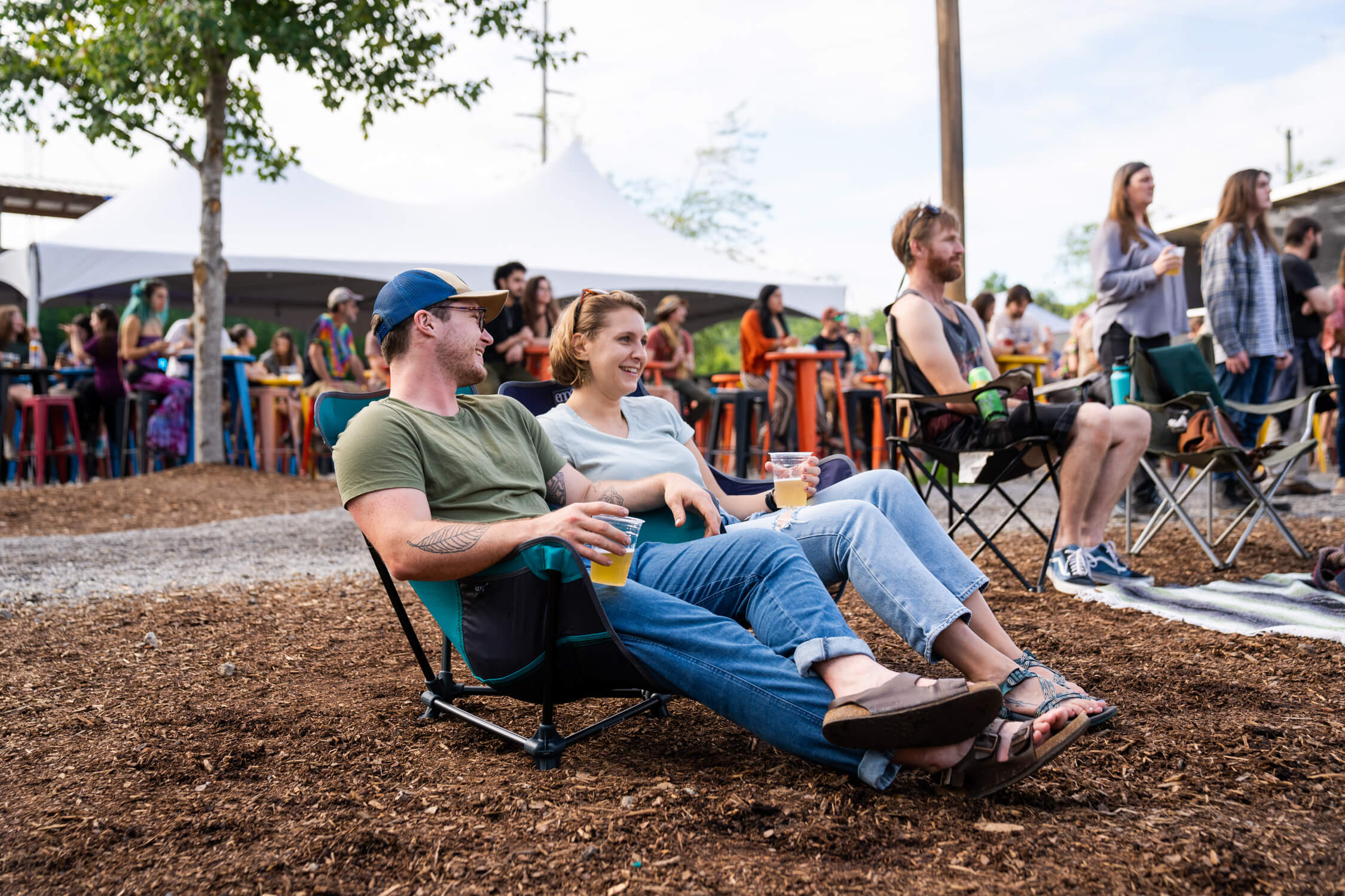 A man and a woman sitting in ENO Lounger Chairs at a festival
