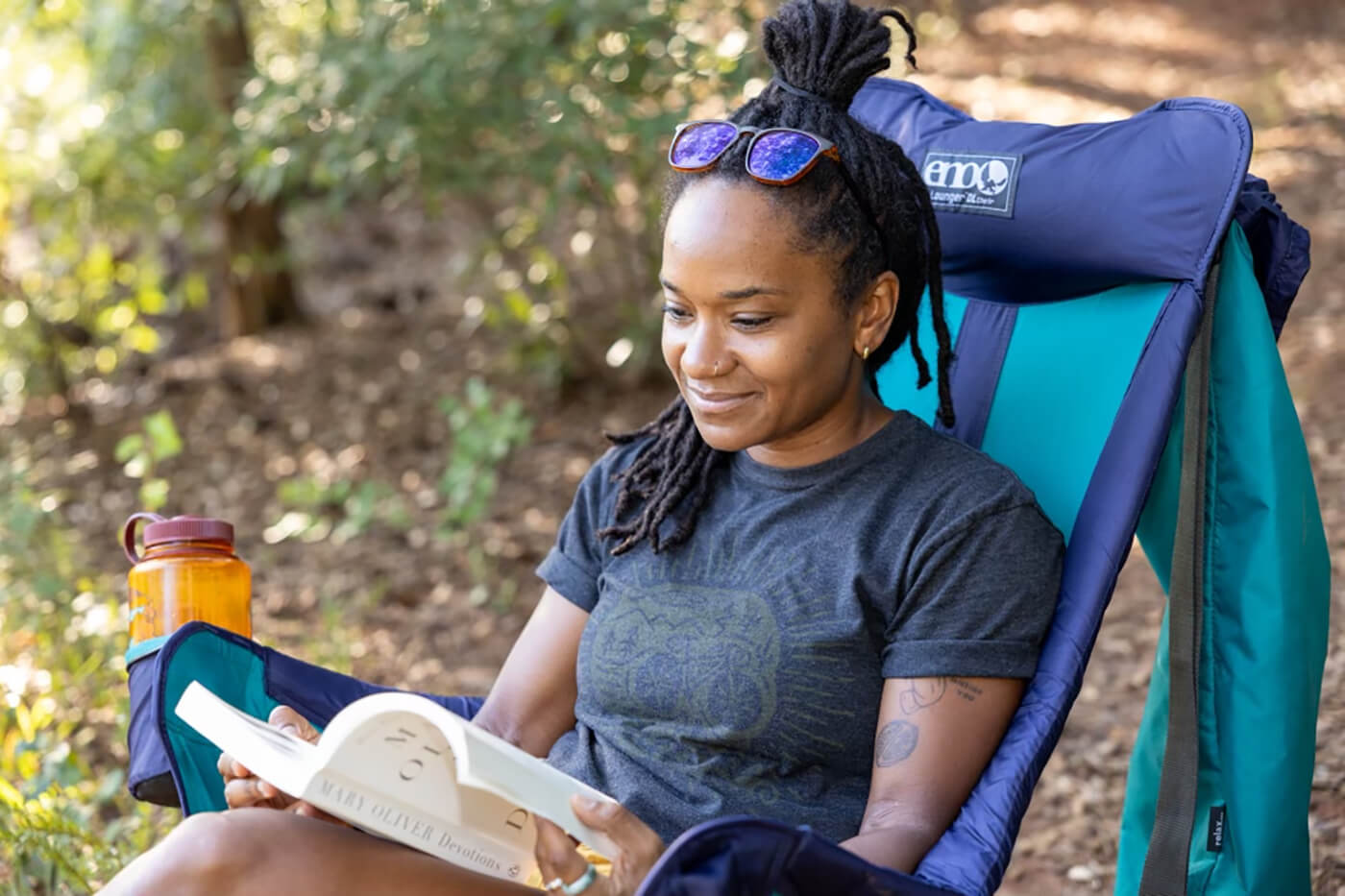 A woman sits in her ENO Lounger DL Chair while reading a book outside