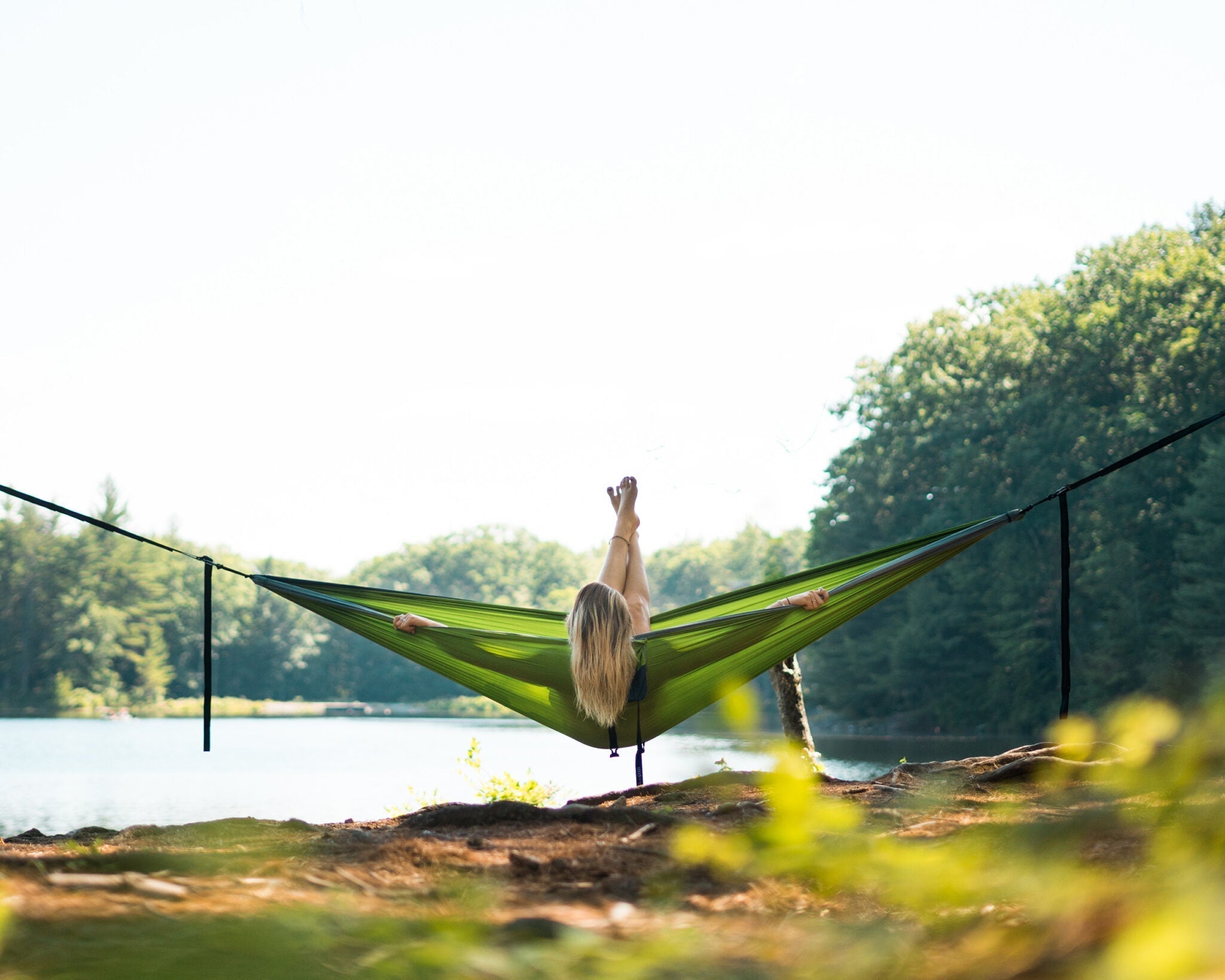 A woman in an ENO hammock looking at a lake