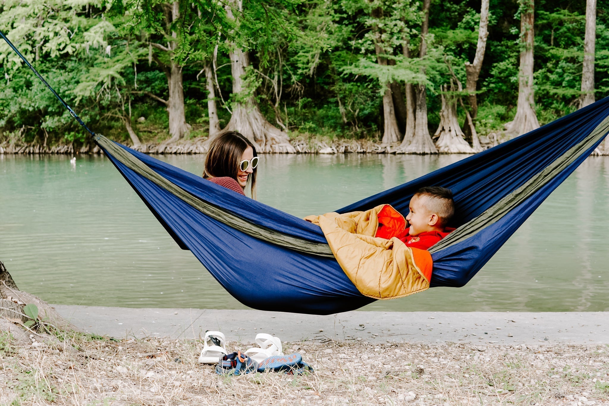 A woman ad a child hammocking in an ENO hammock by the water