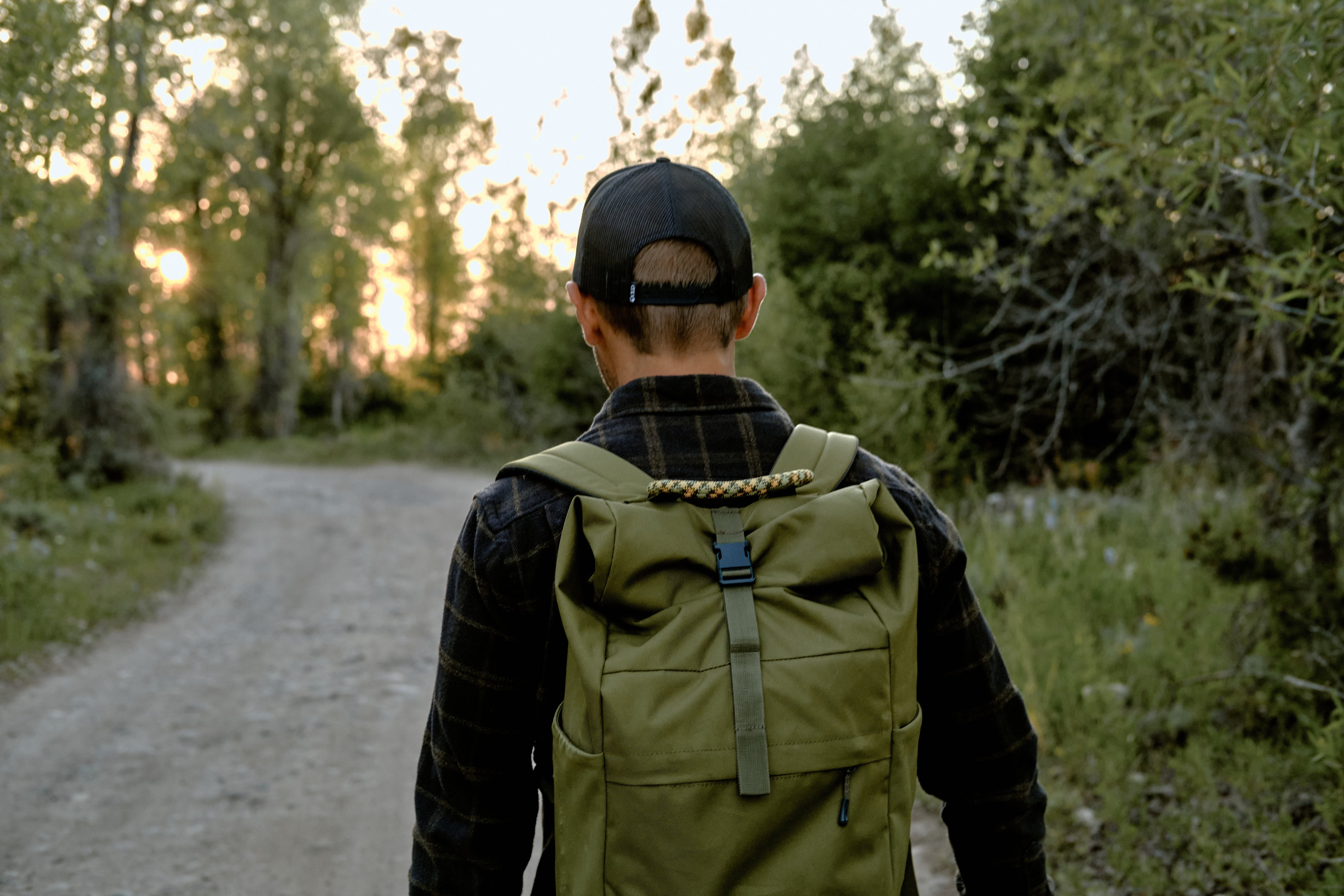 A man walking on a trail with a green ENO backpack on