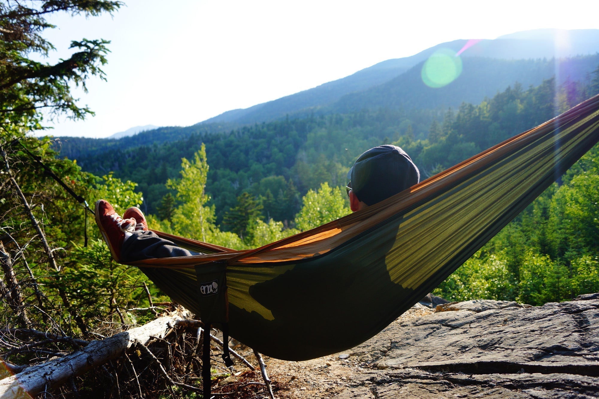 A person hammocking in an ENO Hammock looking at mountain ranges
