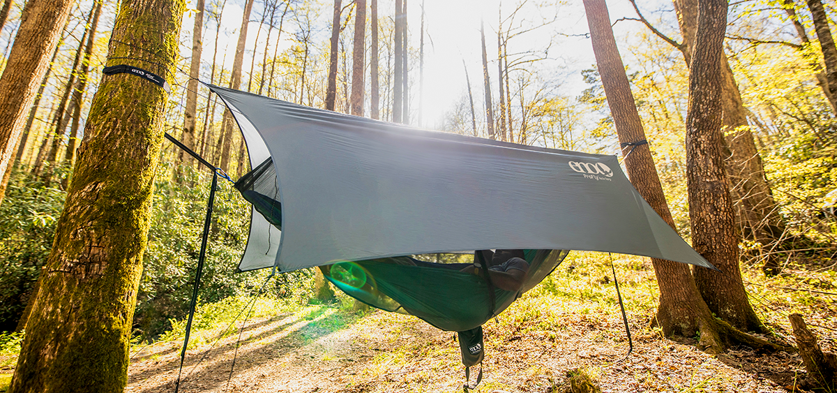A gray tarp hanging over an ENO hammock in the woods