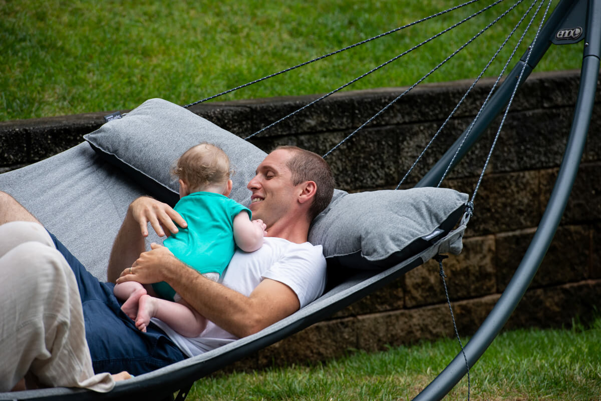 A man holds a baby in an ENO SuperNest Hammock