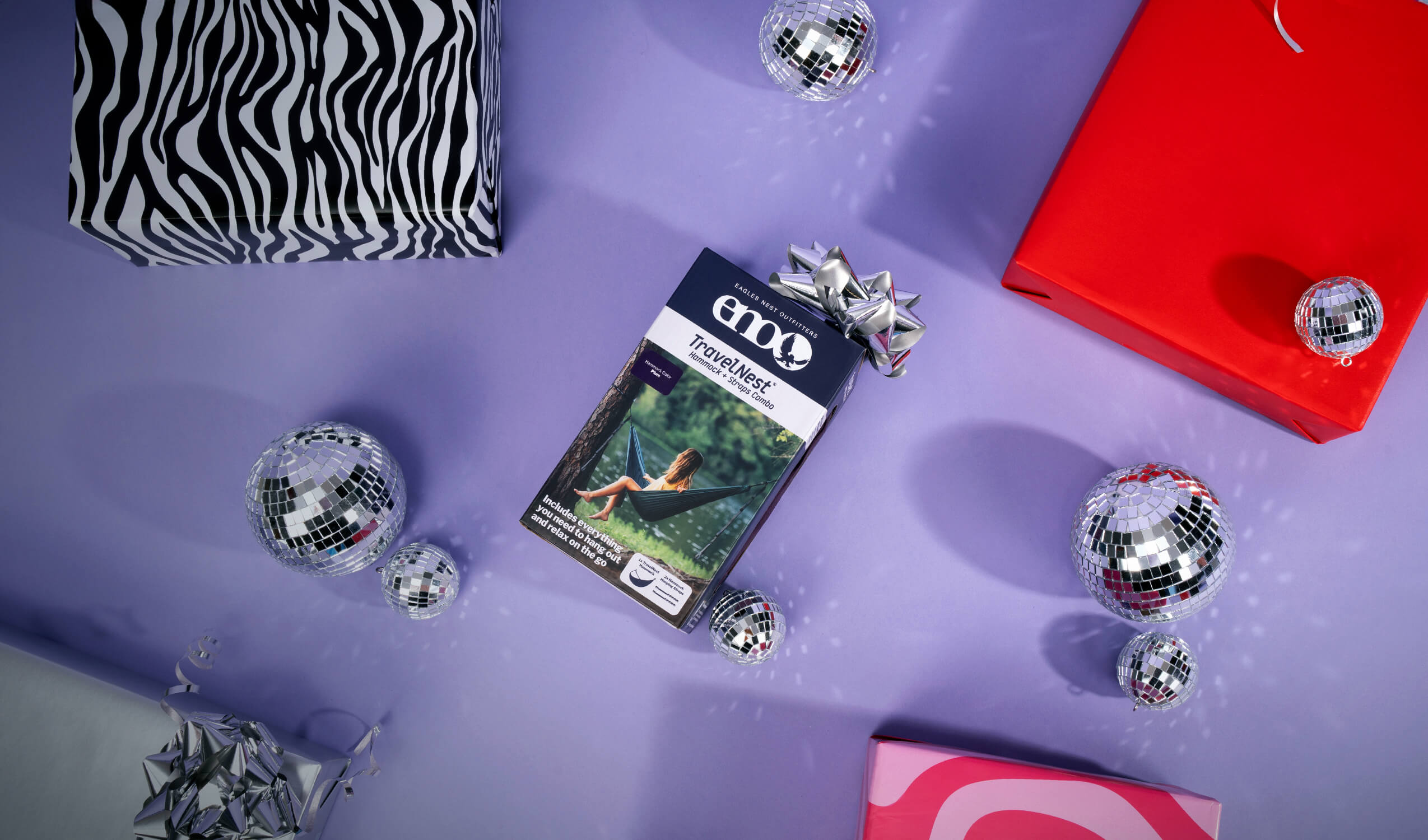 TravelNest Hammock + Straps Combo on a purple surface with disco balls and gift boxes.