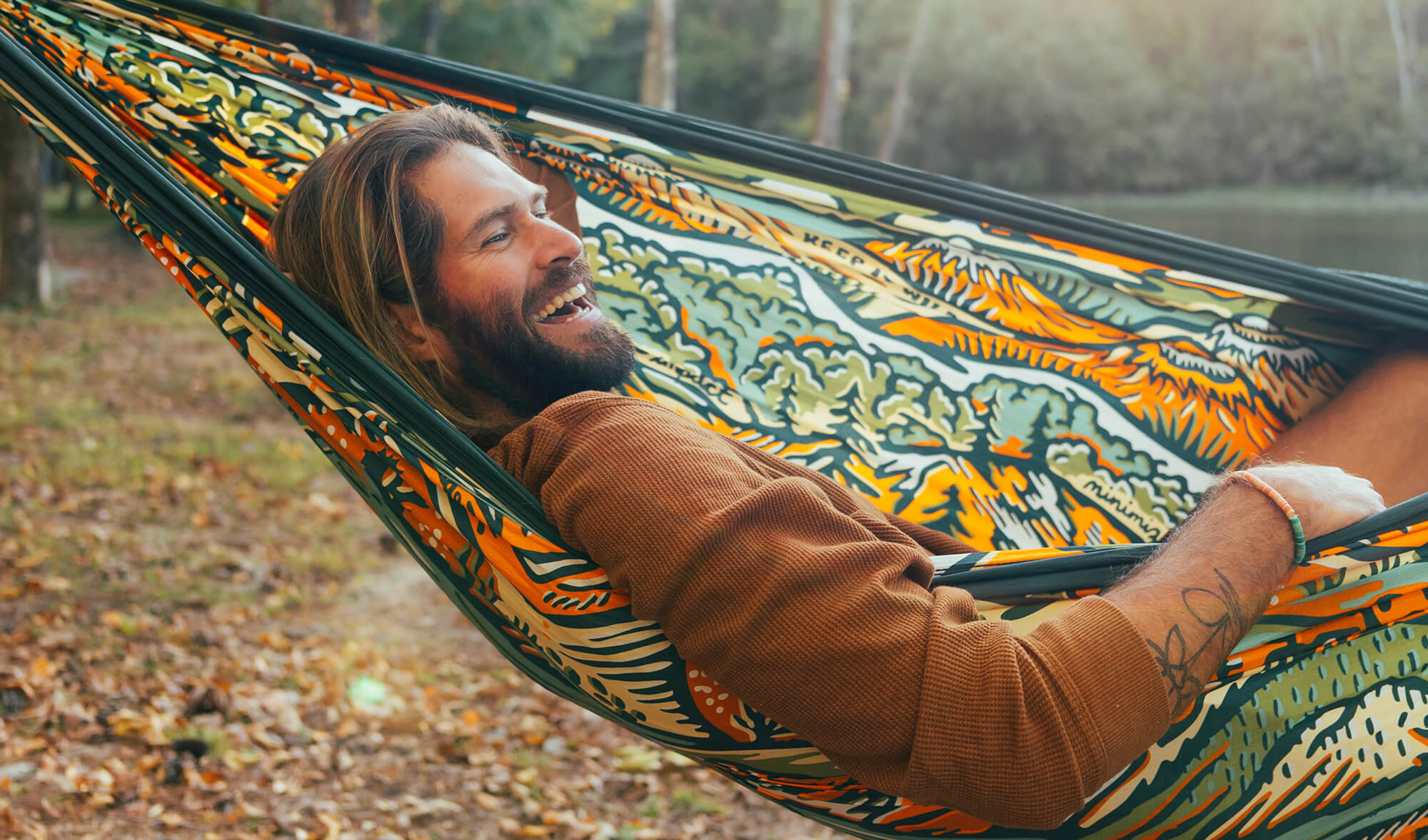 Man with a beard lying in the ENO Keep It Wild Giving Back Hammock surrounded by nature.