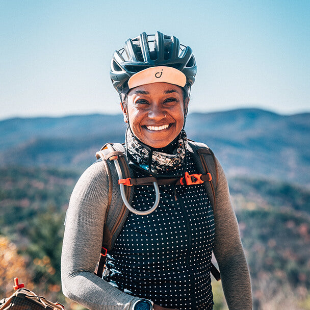 Devin Cowens smiles while bikepacking in the mountains wearing a helmet and cycling gear.