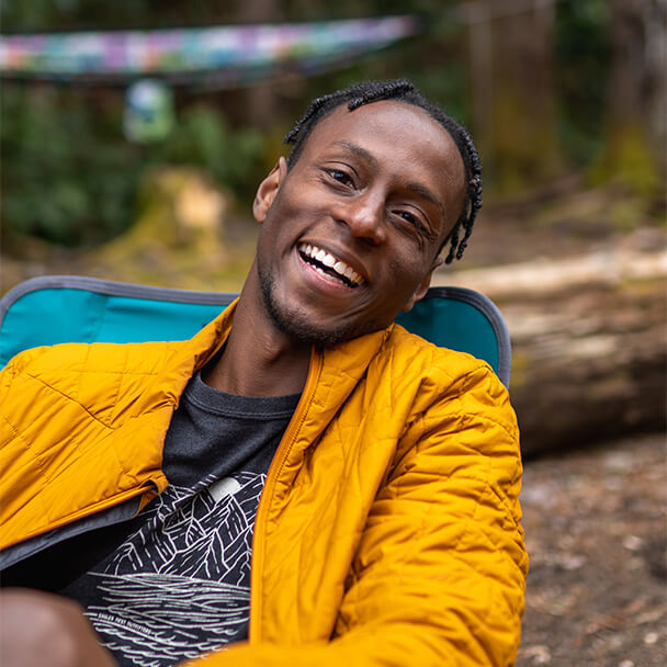 Nathaniel Flowers, an avid adventurer and outdoor photographer and videographer, poses smiling at the camera while sitting in his Eagles Nest Outfitters Lounger SL Chair.