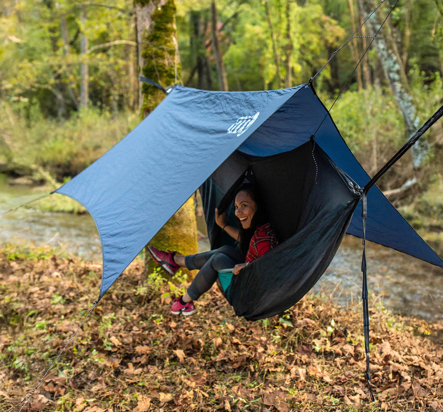 Person sitting inside the ENO OneLink Hammock System in a forest setting.