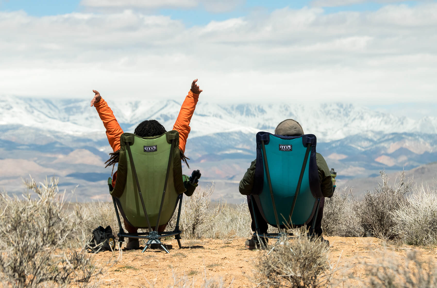 Two people sit in ENO Lounger DL Chairs facing a snowy, mountainous landscape.