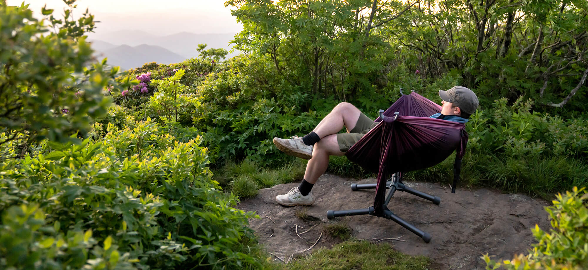Person leaning back relaxing with his leg crossed on top of a mountain in hammock set up on the ENO Parklite Hammock Chair Stand.