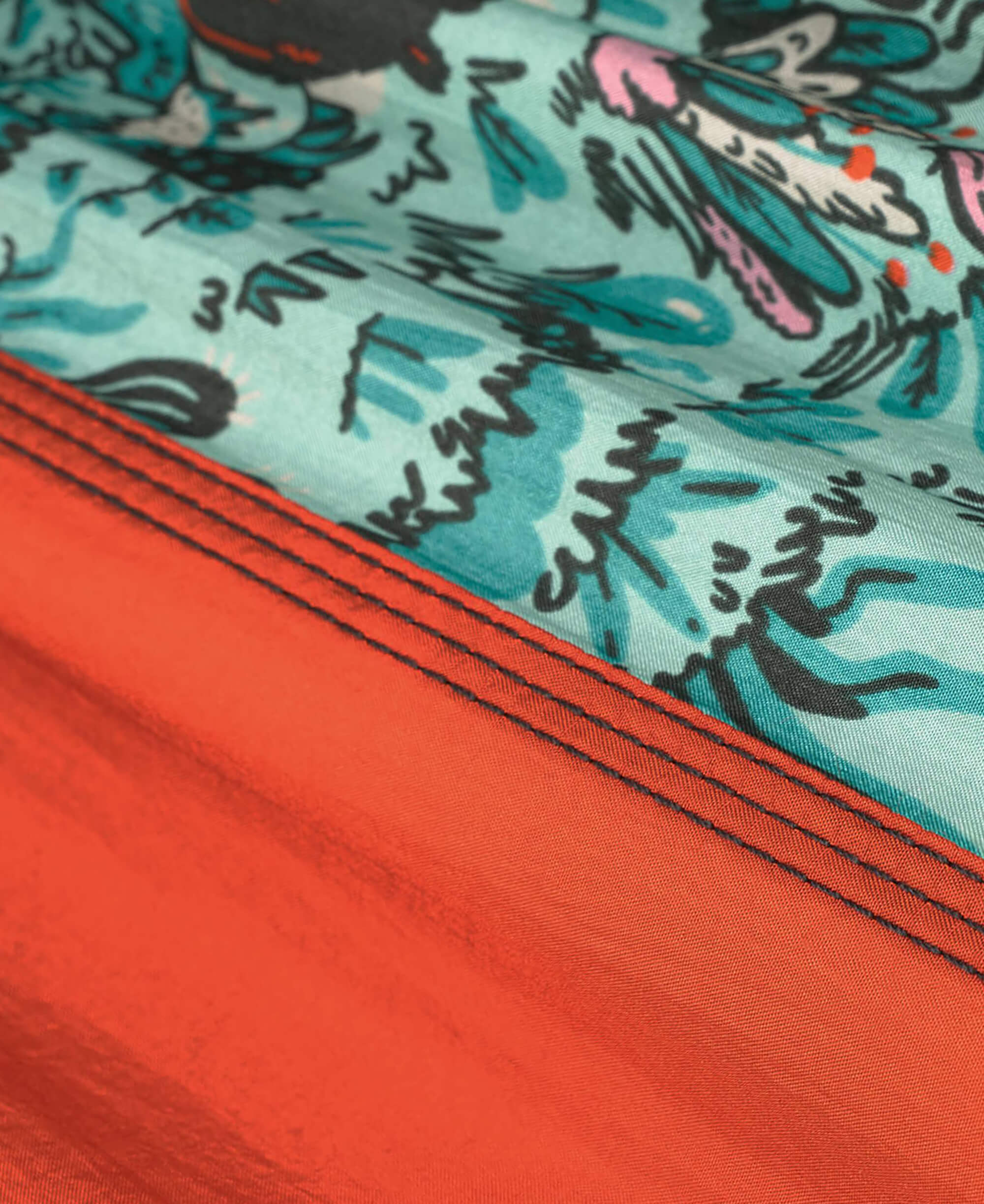 Close-up of a fabric with a colorful pattern and a red border.