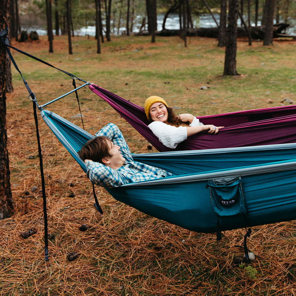 A middle-aged couple relaxes in an ENO two-hammock suspension system in the cooler winter season.
