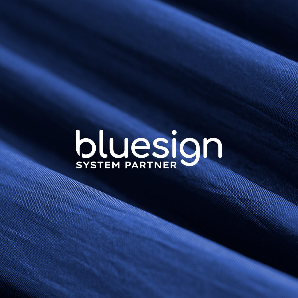 bluesign System Partner logo with detail of blue fabric in background.