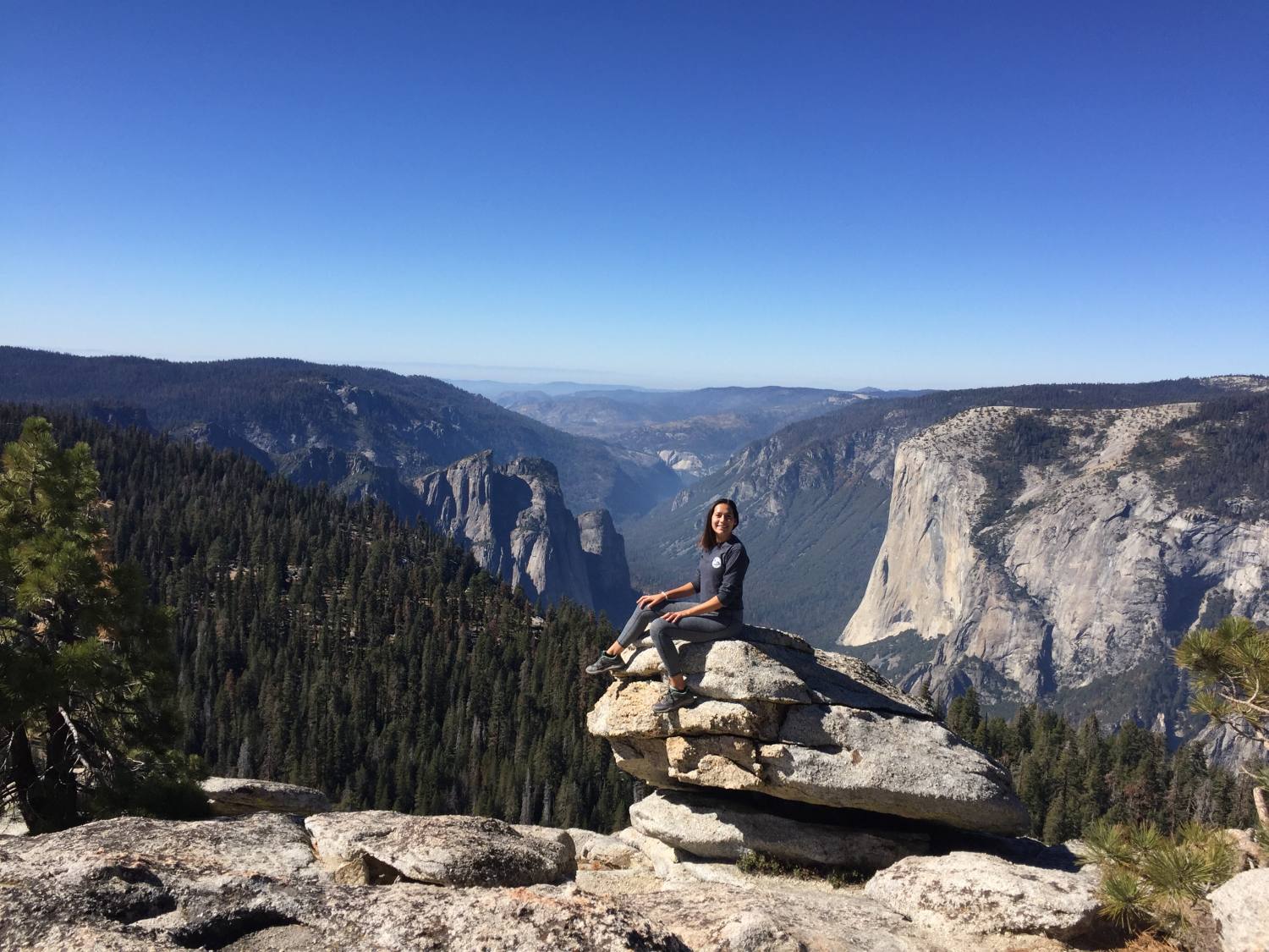 woman sitting on a stack of rocks at a viewpoint in Yosemite National Park
