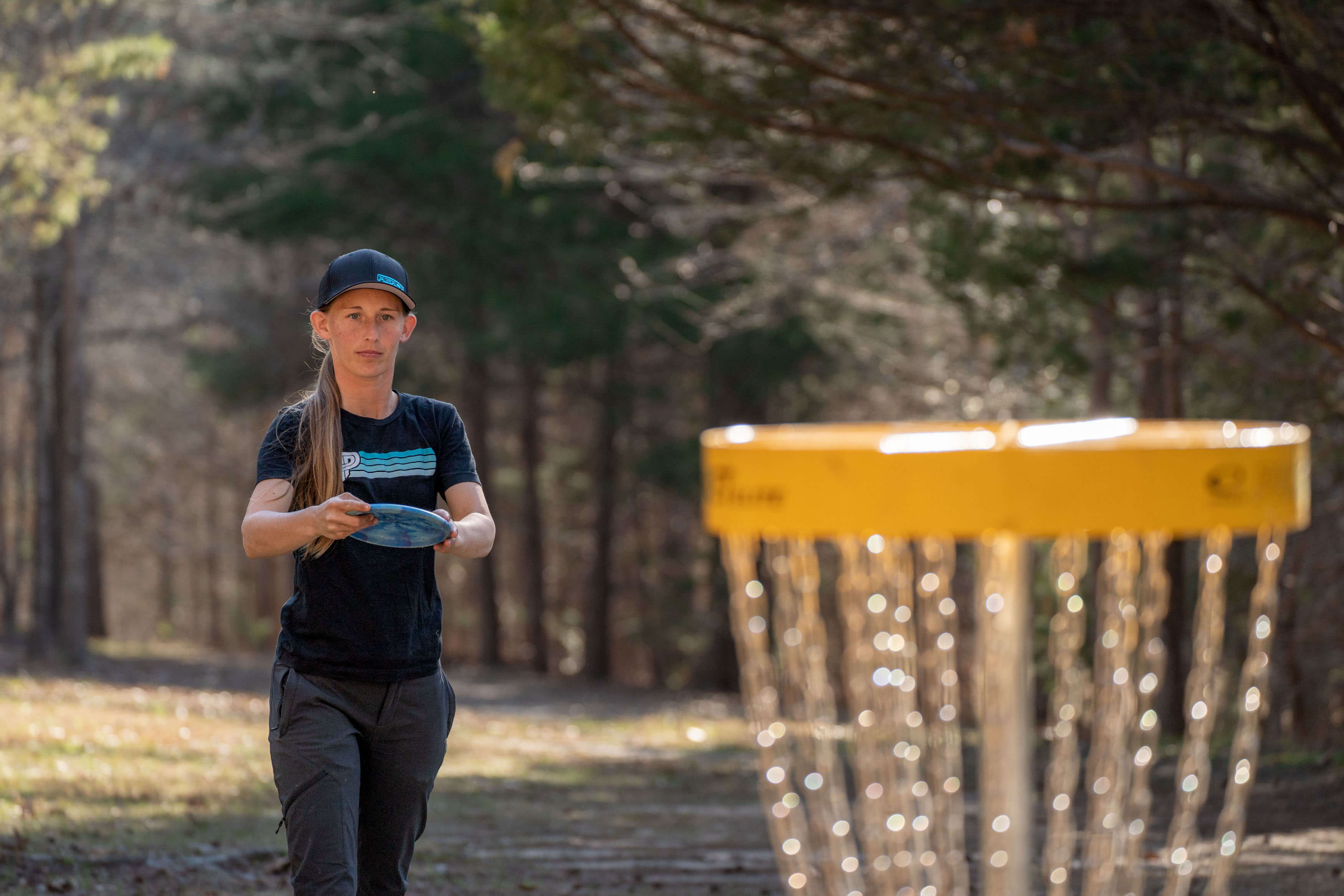 Paige Pierce is about to throw a disc into the goal while disc golfing.