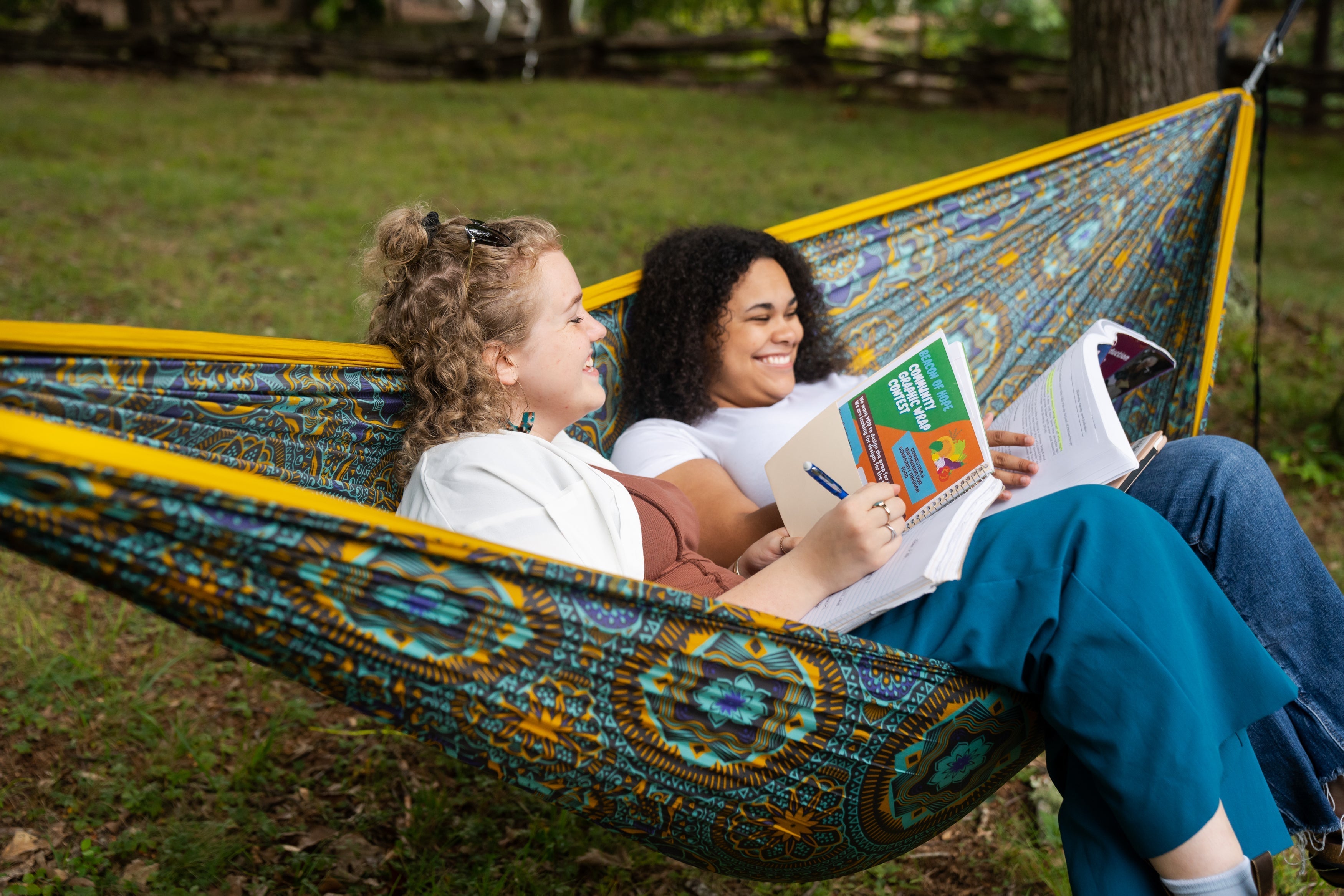 Two girls in one ENO DoubleNest Hammock doing school work on notebooks