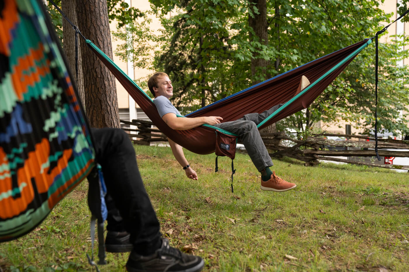 Man sits in ENO hammock while another man sits in another ENO hammock next to him