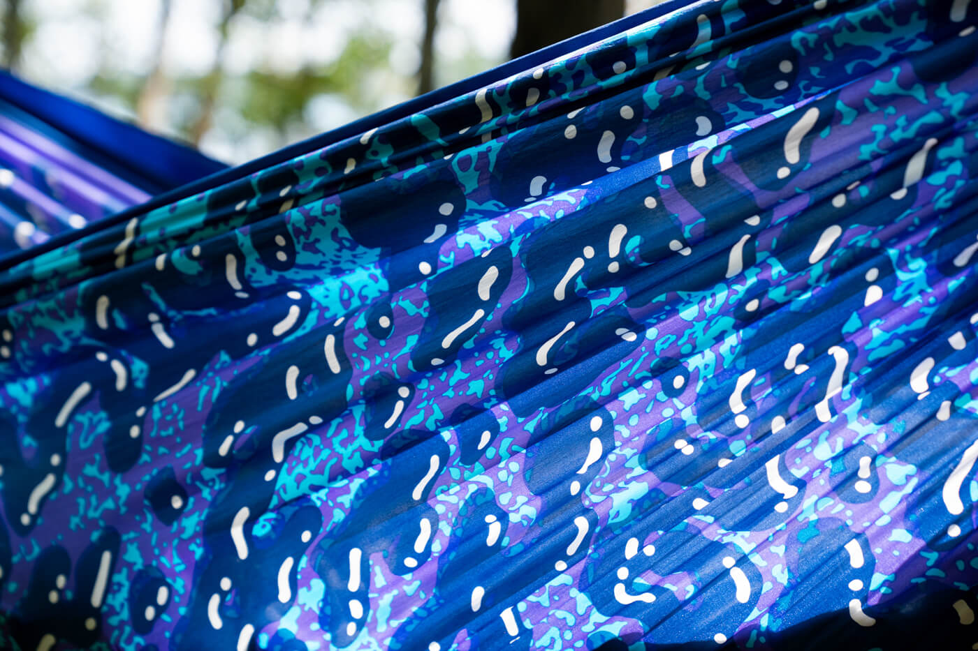 A close up detail shows the Splash DoubleNest Hammock Print by ENO. The print is a mix of blue, purple and while blobs.