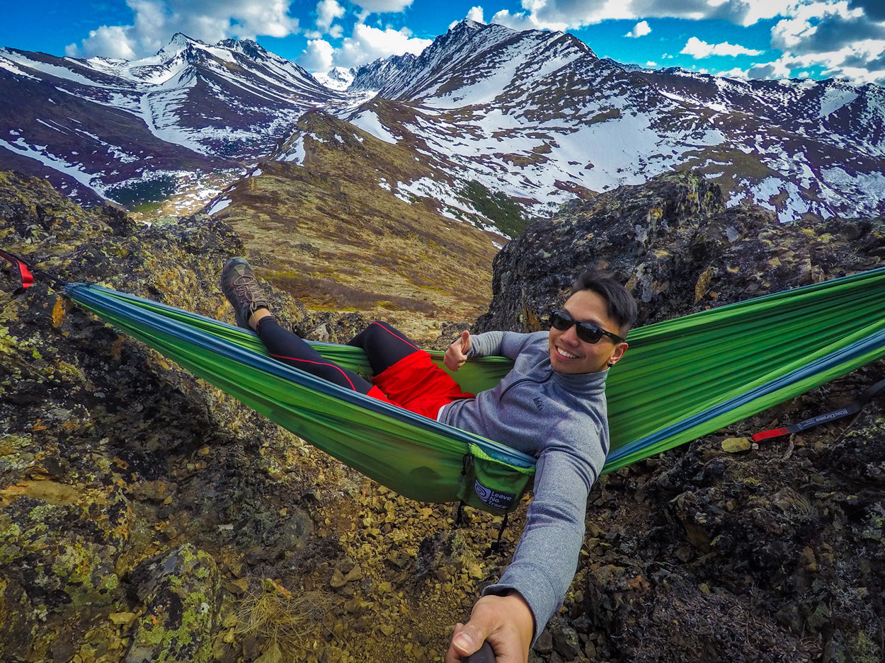 man hanging in a hammock in the mountains