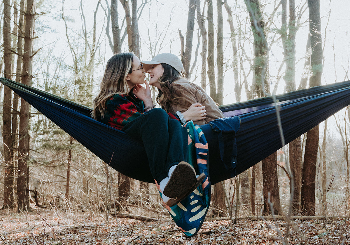 A couple about to kiss in an ENO hammock in the woods