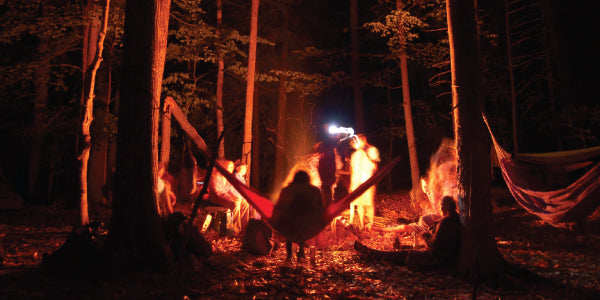 hammock hanging in front of a campfire in the woods