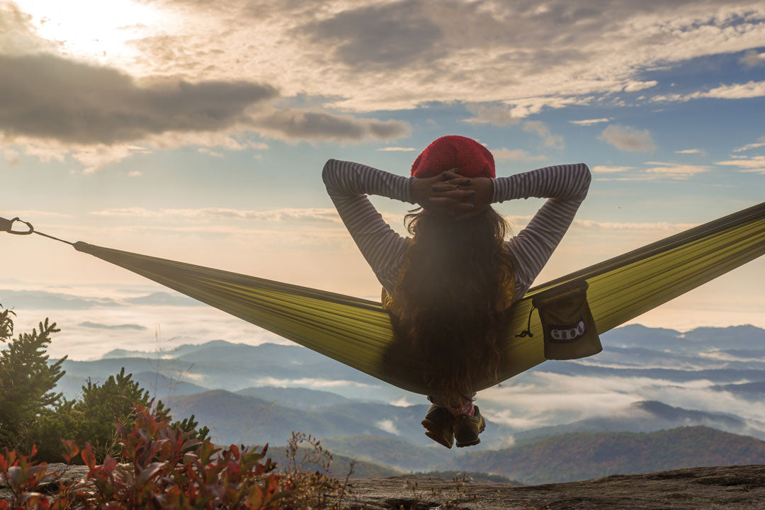 A girl hammocking in an ENO Hammock and watching the clouds move along mountain ranges