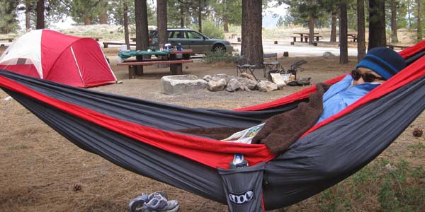 man bundled up in a hammock while camping