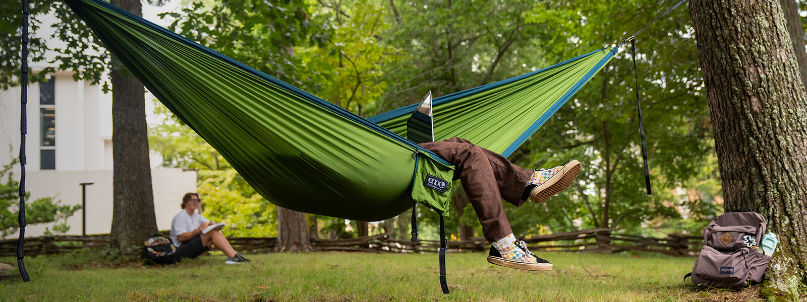 Student lounging in ENO DoubleNest Hammock with their feet hanging out.