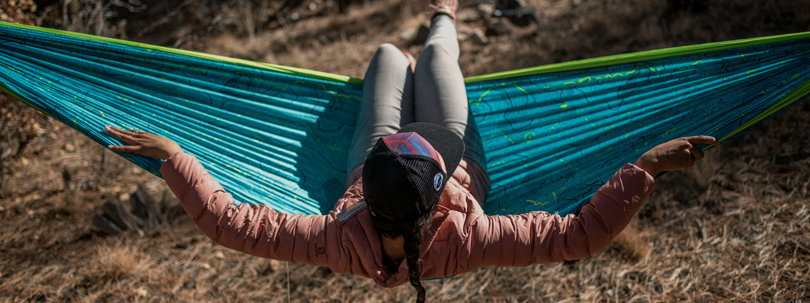 A person sitting in an ENO giving back hammock with their arms stretched out. 