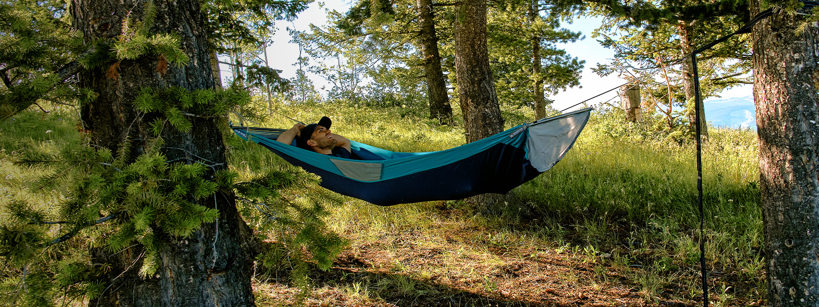 A person laying back in an ENO SkyLoft Hammock in forest.