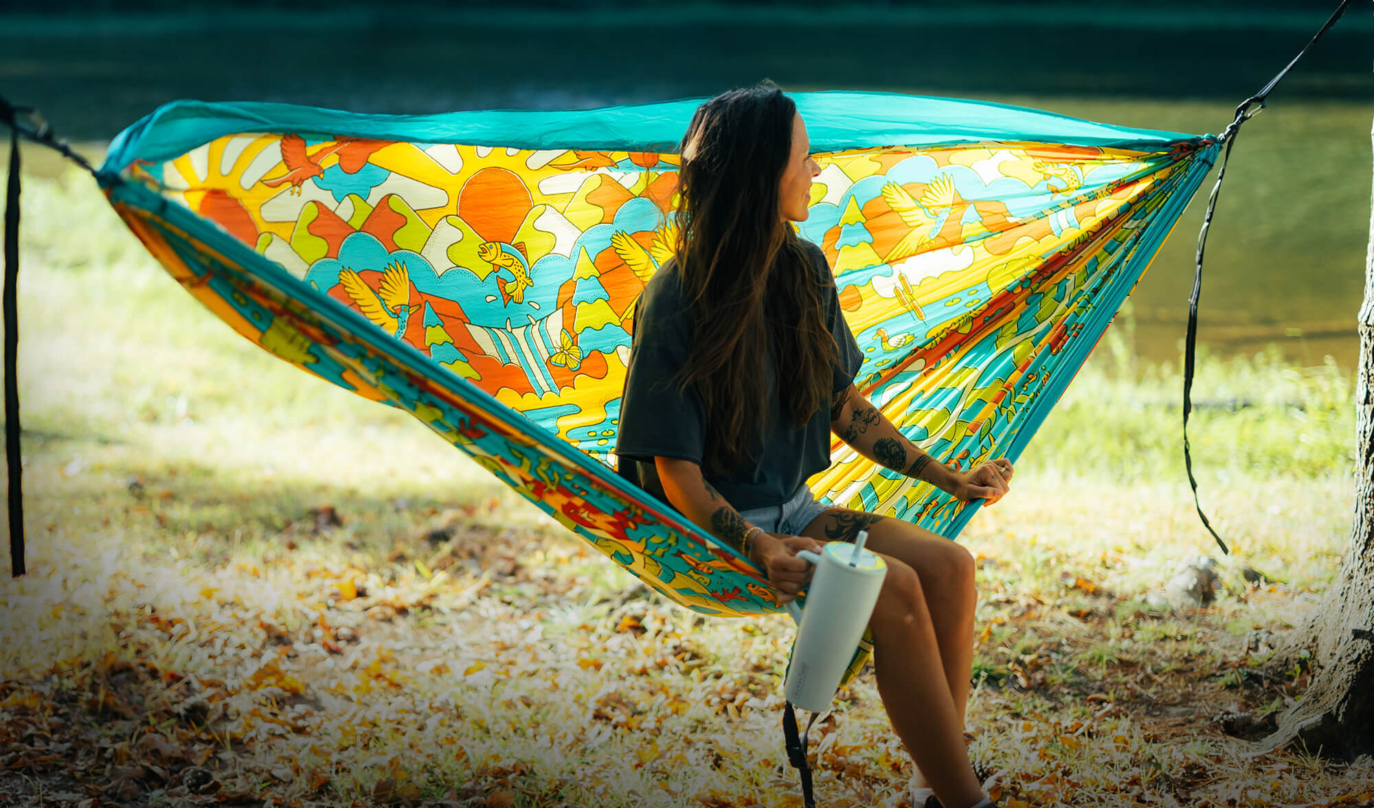 Person sitting in the ENO Vibrant Earth Giving Back Hammock with a scenic background