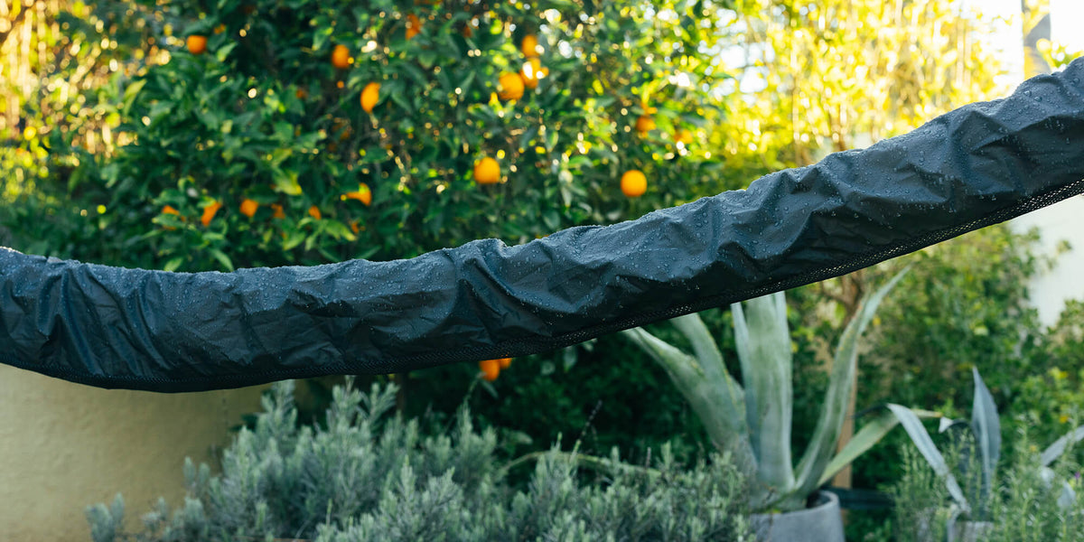 Detail of the Overcast Hammock Cover in backyard setting with water droplets beading on exterior  