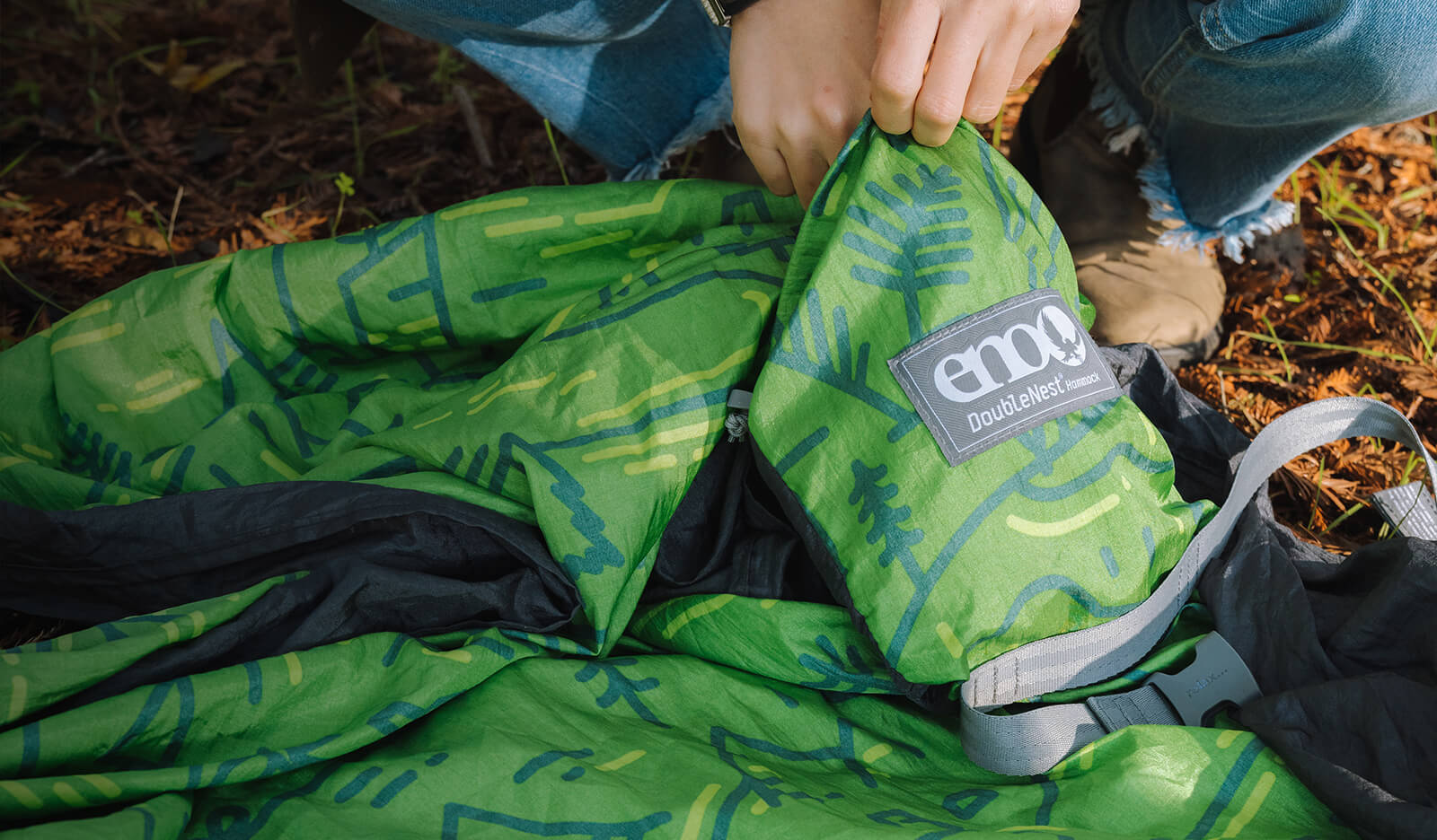 Close up photo of ENO DoubleNest Hammock Giving Back Print being backed into its included stuff sack. 