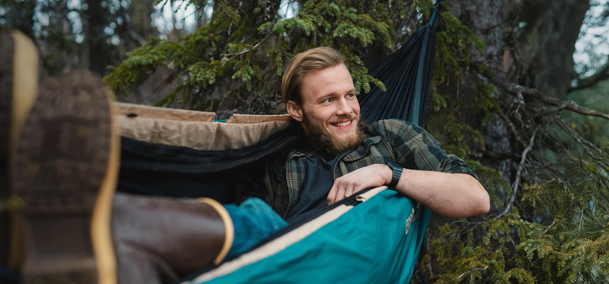 Person laying back in an ENO hammock with Ember UnderQuilt, while looking out smiling.