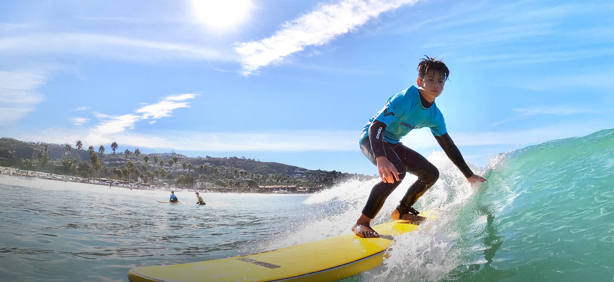 Person surfing on a yellow board with a scenic beach in the background