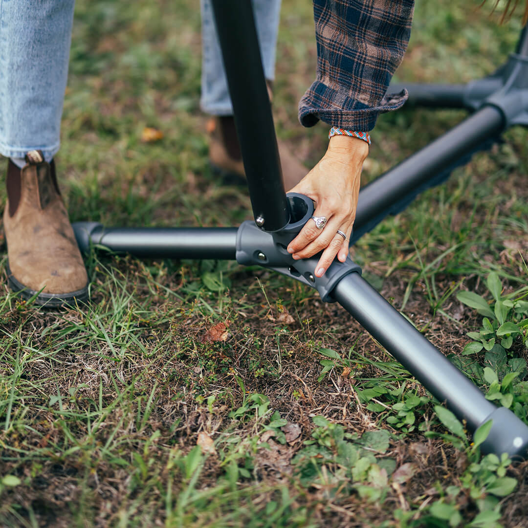 Person setting up the ENO Parklite Hammock Stand in grassy field, focusing on the No-Tools-Needed construction.