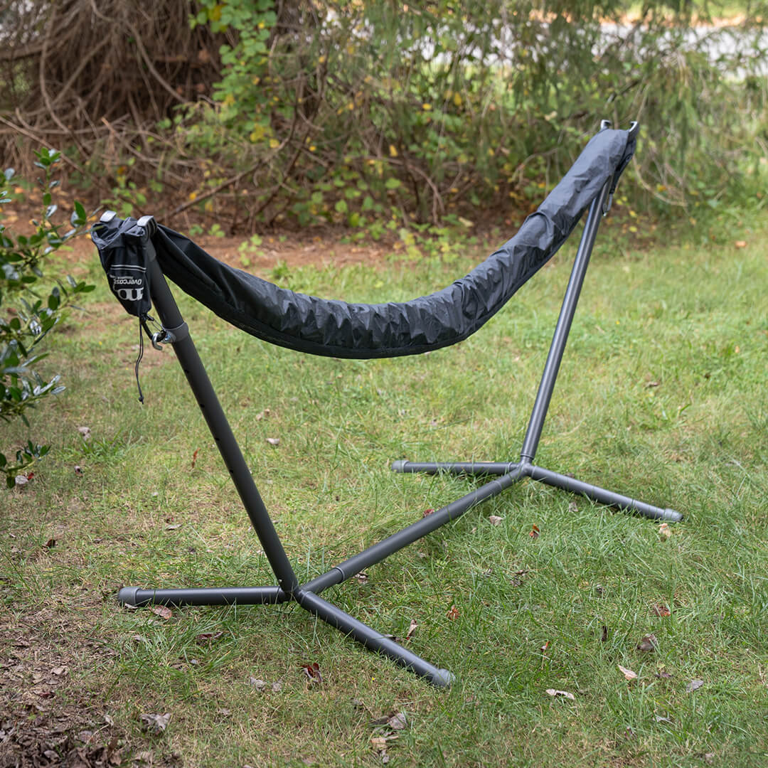 ENO Overcast Hammock Cover on a hammock stand in an outdoor setting with grass and plants.