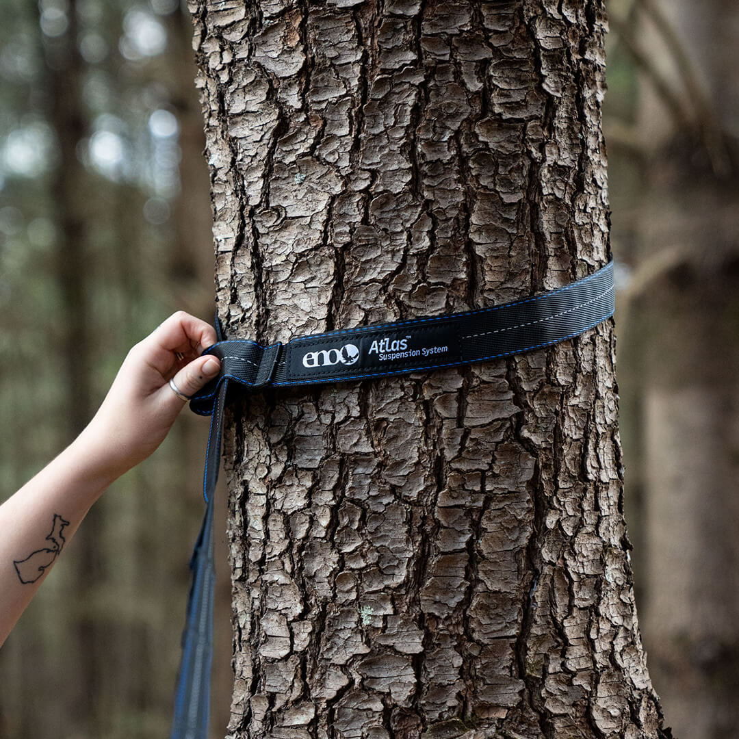 Person setting up ENO Atlas Hammock Straps around bark of tree.