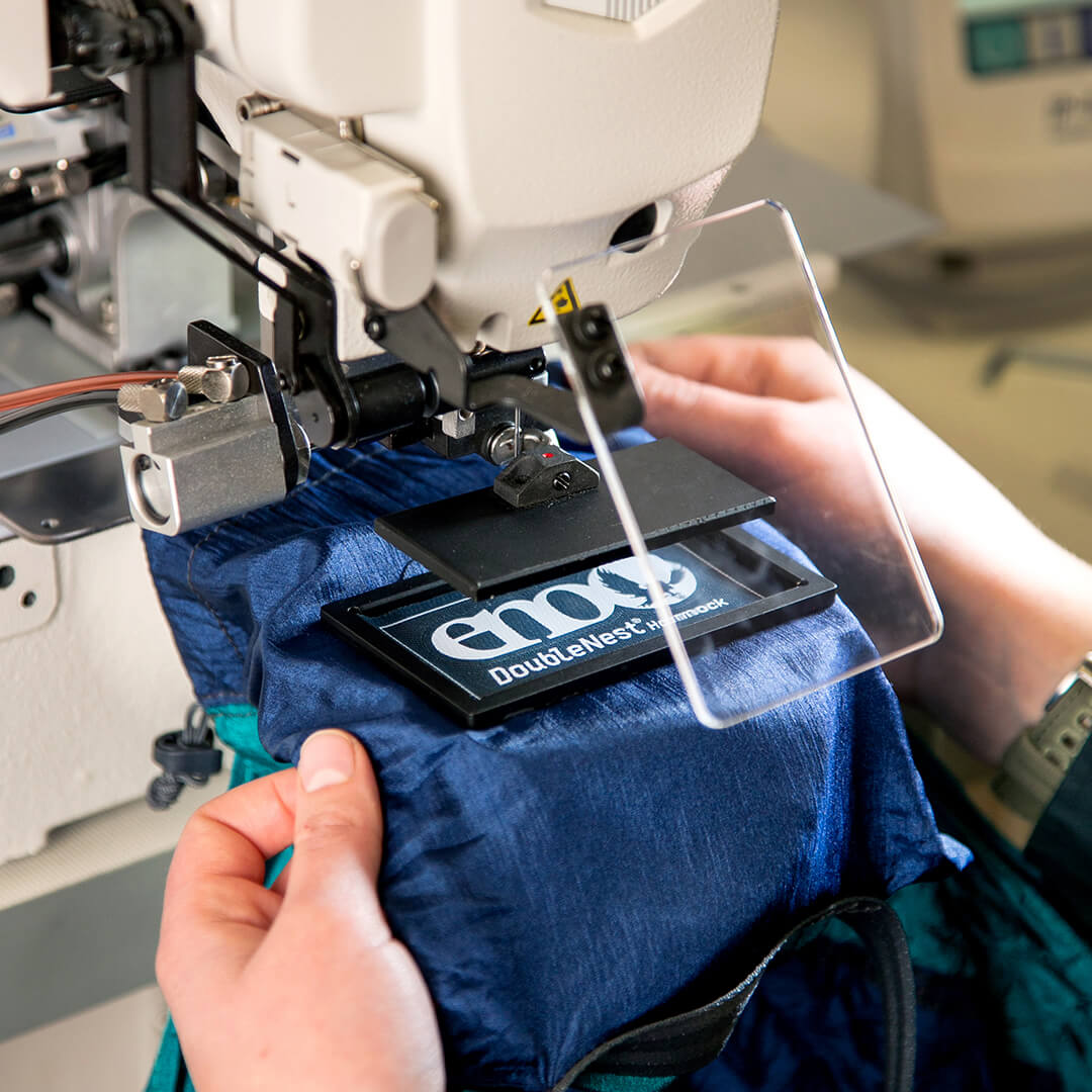 A person using a sewing machine to repair an ENO hammock.