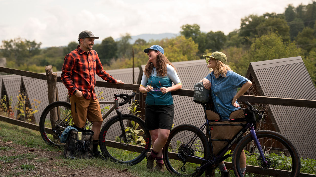 Two women and one man wear Cognative MTB and Recover Brand clothing while hanging out with mountain bikes at Wrong Way Campground in Asheville, NC. 