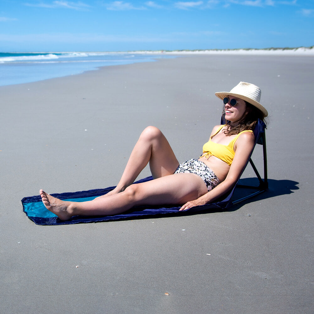 A woman in a bathing suit relaxing and looking at the ocean on an ENO ground chair.