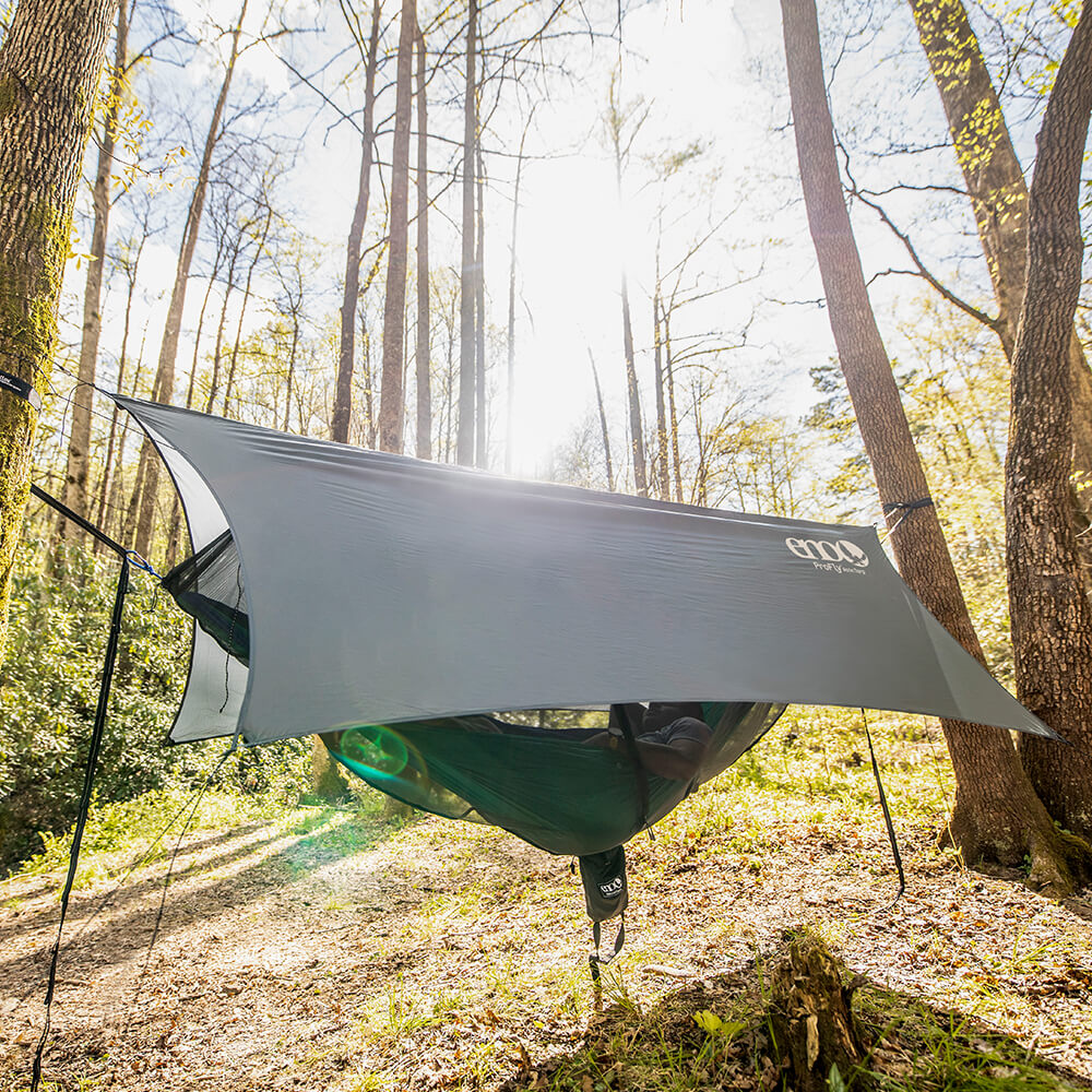 ENO hammock tent consisting of rain tarp, bug net, hammock, and hammock straps set up in the woods.