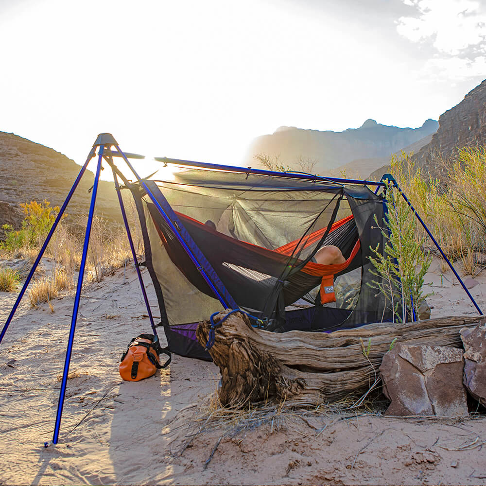 A person relaxing in an ENO hammock tent in a desert environment. 