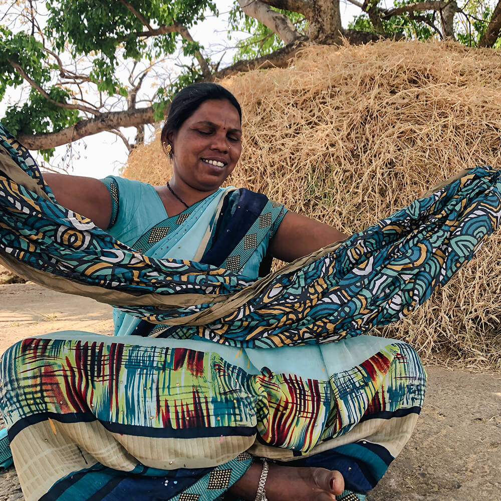 Gond community member holding Roots Studio ENO giving back hammock while sitting down.