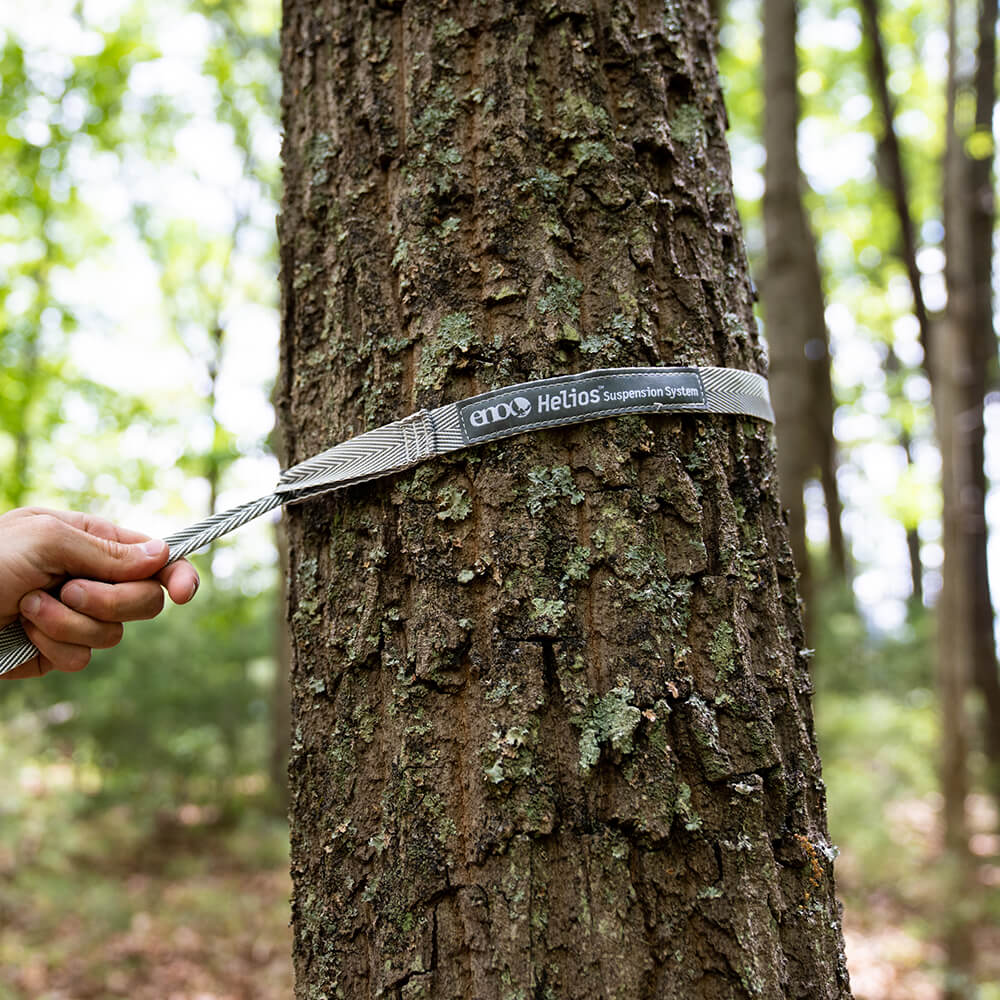 Close-up of ENO hammock tree straps being tightened around the bark of a tree in the woods.